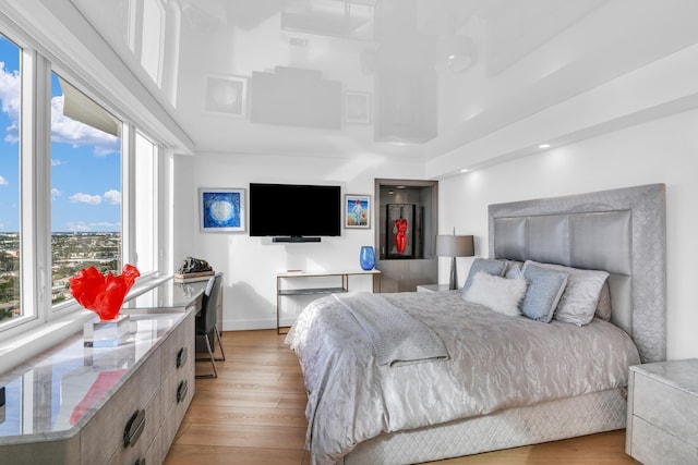 bedroom with a towering ceiling and light hardwood / wood-style flooring