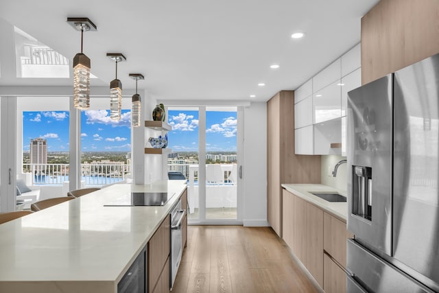 kitchen with stainless steel appliances, light countertops, hanging light fixtures, white cabinets, and modern cabinets