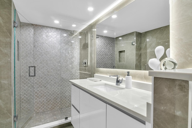 bathroom featuring vanity, walk in shower, and tile walls