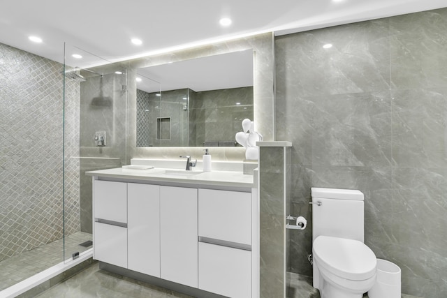 bathroom with walk in shower, vanity, toilet, and tile walls