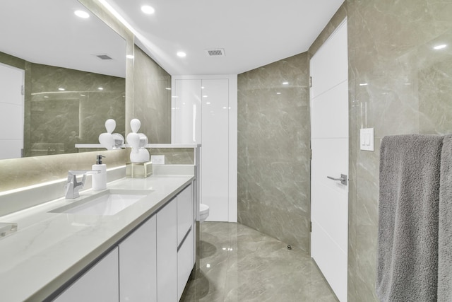 bathroom with vanity, toilet, and tile walls