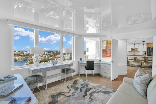 office area with plenty of natural light, wood-type flooring, and a towering ceiling