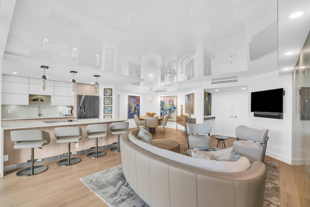 living area featuring light wood-style floors, baseboards, and a high ceiling