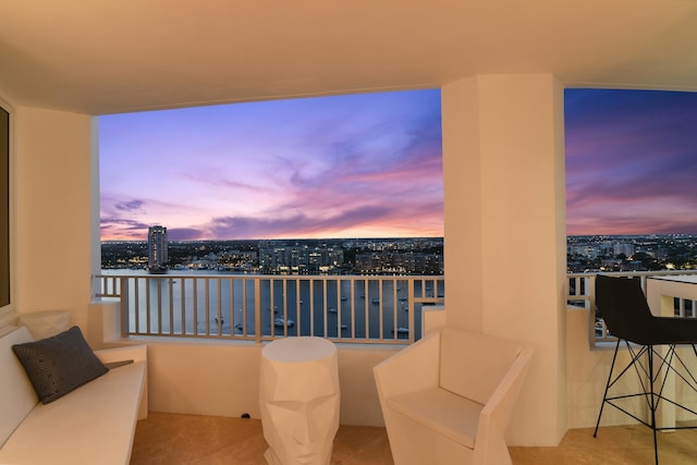 balcony at dusk featuring a water view