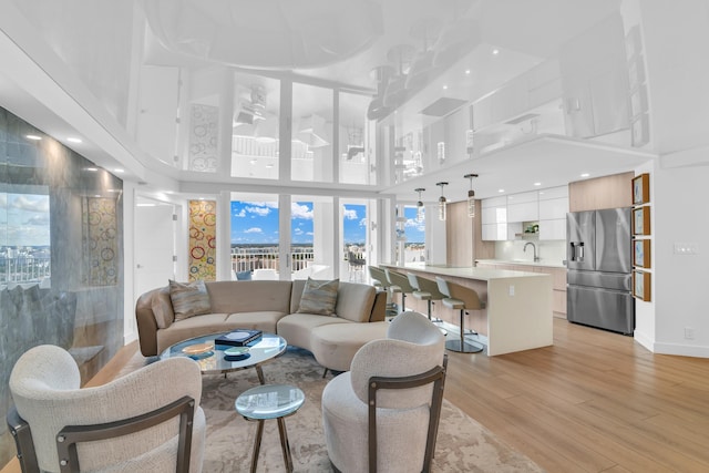 living room with light wood-type flooring, sink, and a high ceiling