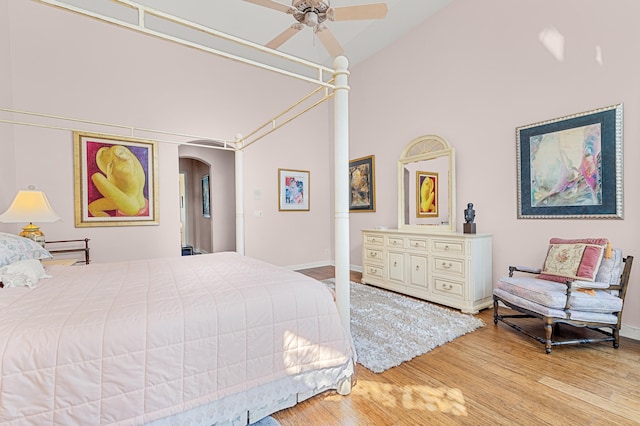 bedroom with hardwood / wood-style flooring, high vaulted ceiling, and ceiling fan