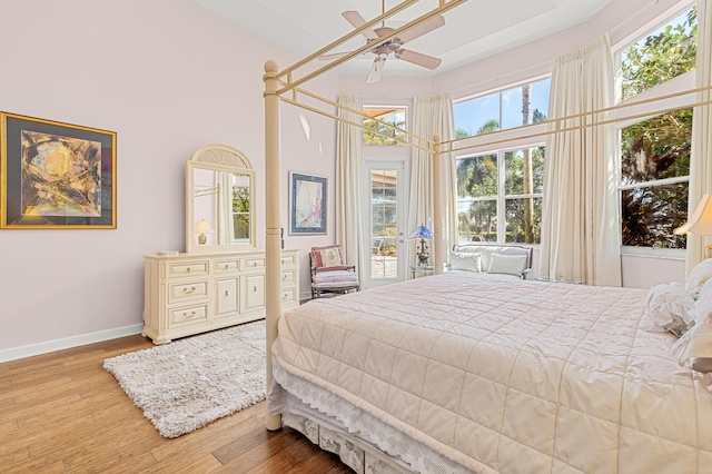 bedroom with ceiling fan, wood-type flooring, and a high ceiling