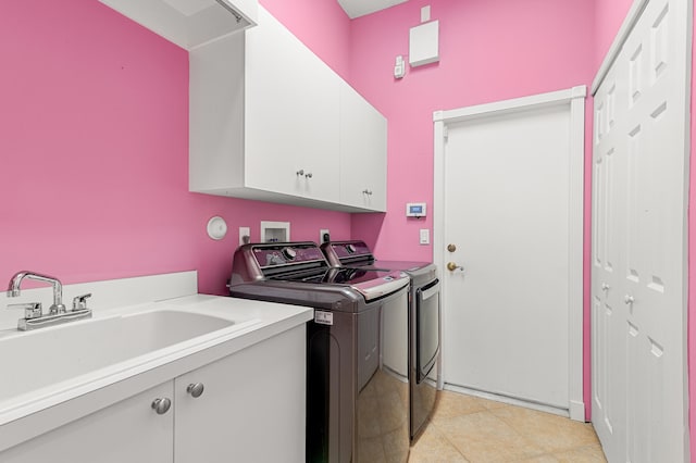 washroom with cabinets, light tile patterned floors, sink, and washing machine and clothes dryer