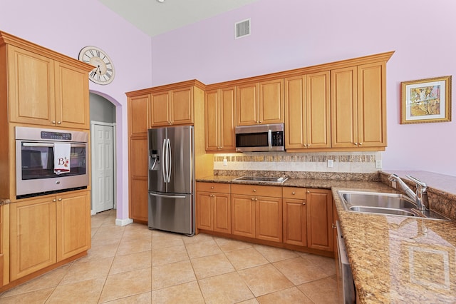 kitchen featuring appliances with stainless steel finishes, stone countertops, sink, and light tile patterned floors