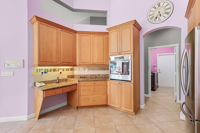 kitchen with light stone counters, light tile patterned floors, decorative backsplash, and stainless steel appliances