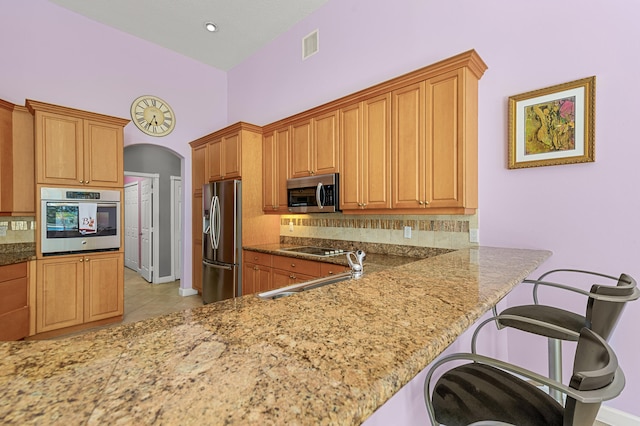 kitchen with stainless steel appliances, sink, a breakfast bar area, and kitchen peninsula