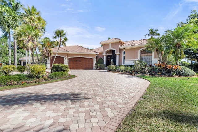 mediterranean / spanish home featuring a garage and a front yard