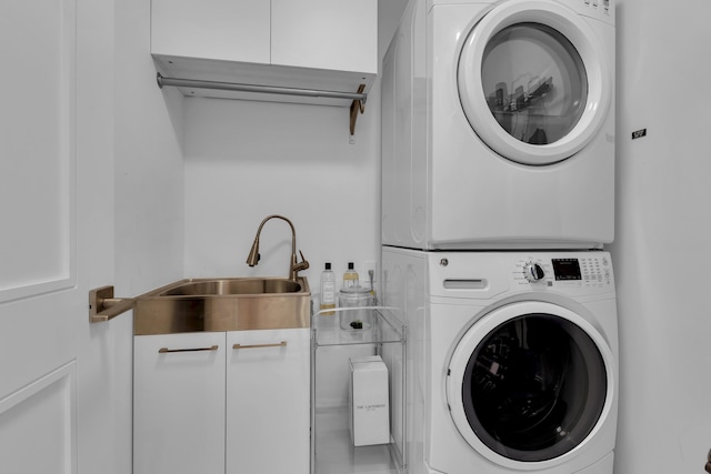 laundry area featuring stacked washer and dryer, sink, and cabinets