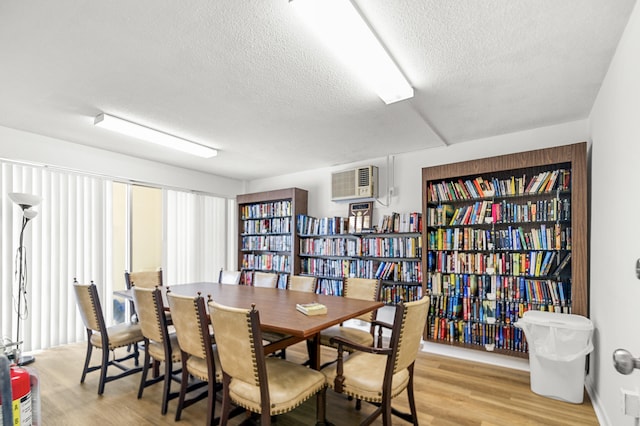 dining room featuring a textured ceiling, light hardwood / wood-style floors, and a wall unit AC