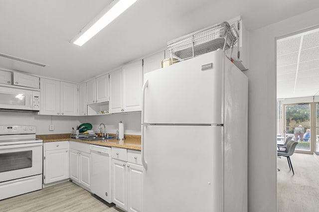 kitchen with light wood-type flooring, sink, white appliances, and white cabinetry