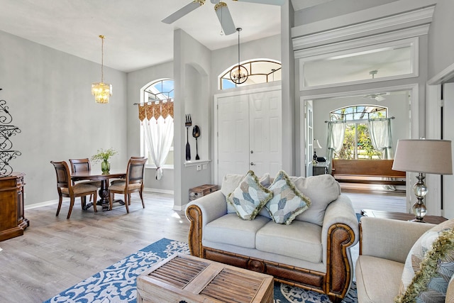 living room with ceiling fan with notable chandelier and light wood-type flooring