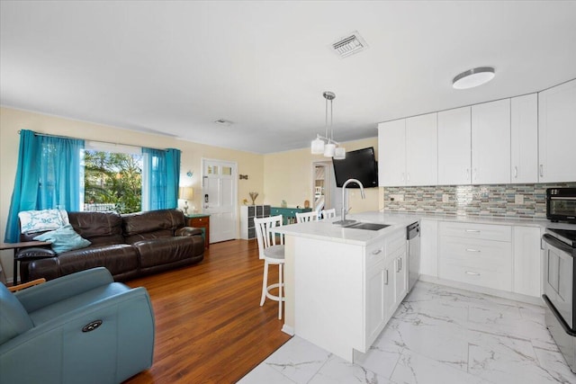 kitchen with white cabinetry, kitchen peninsula, decorative light fixtures, a breakfast bar area, and appliances with stainless steel finishes