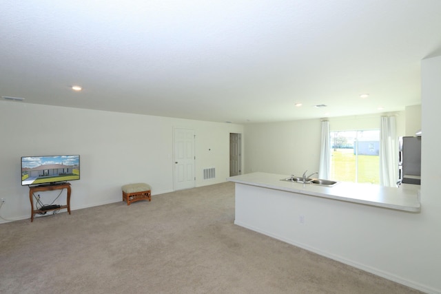 unfurnished room featuring light carpet and sink