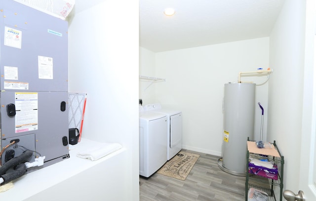 washroom featuring washing machine and dryer, electric water heater, light hardwood / wood-style flooring, and heating unit