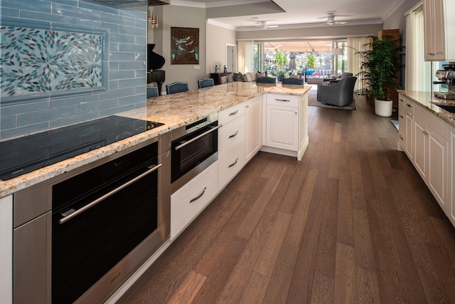 kitchen featuring tasteful backsplash, black electric stovetop, oven, white cabinets, and light stone counters