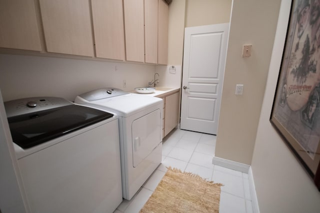 clothes washing area featuring washer and clothes dryer, sink, light tile patterned flooring, and cabinets