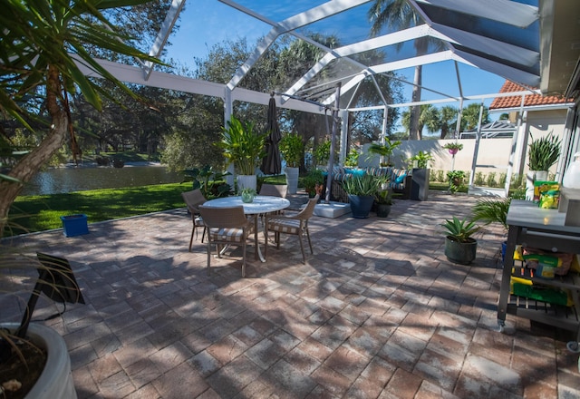 view of patio featuring a lanai and a water view