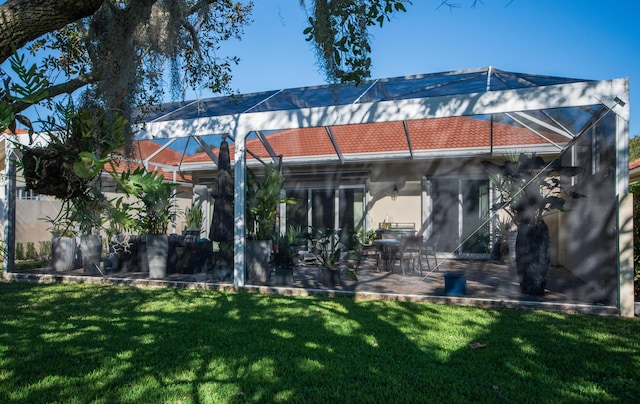 back of house with a lawn, a patio area, and glass enclosure