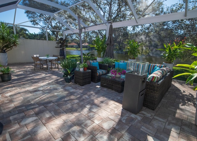 view of patio / terrace with a lanai, a water view, and an outdoor hangout area