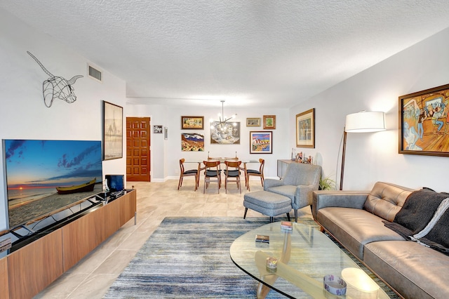 living room featuring light tile patterned floors, a textured ceiling, and a notable chandelier