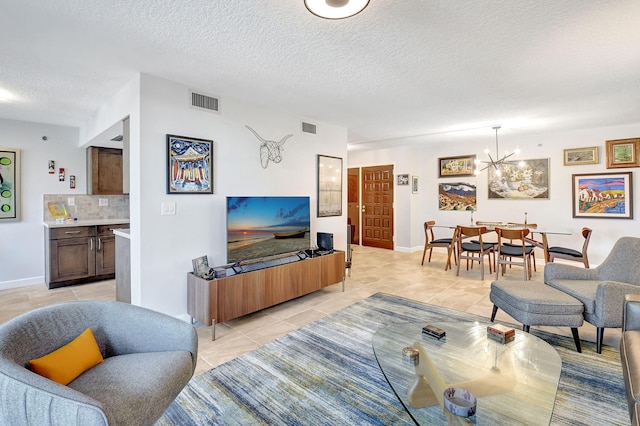 living room featuring a notable chandelier, light tile patterned flooring, and a textured ceiling