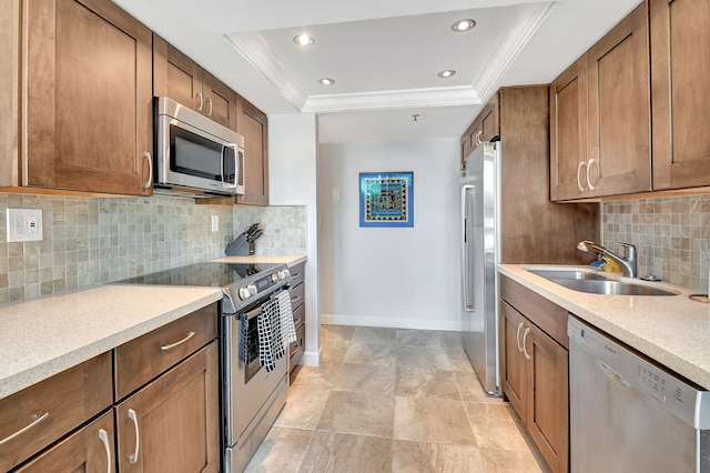 kitchen featuring sink, a raised ceiling, ornamental molding, and stainless steel appliances