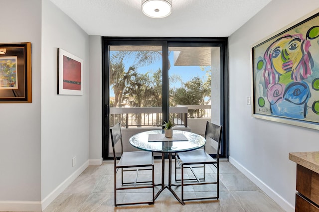 tiled dining space featuring a textured ceiling and a wall of windows