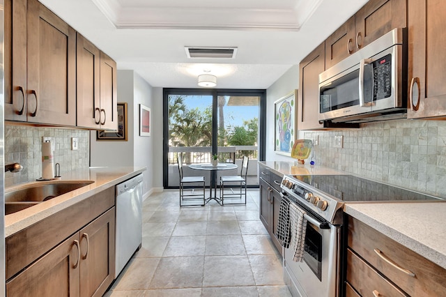 kitchen with a tray ceiling, ornamental molding, and appliances with stainless steel finishes