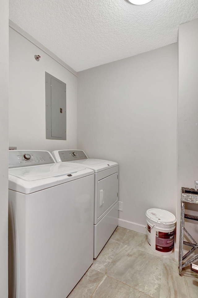 clothes washing area featuring a textured ceiling, electric panel, and washing machine and dryer