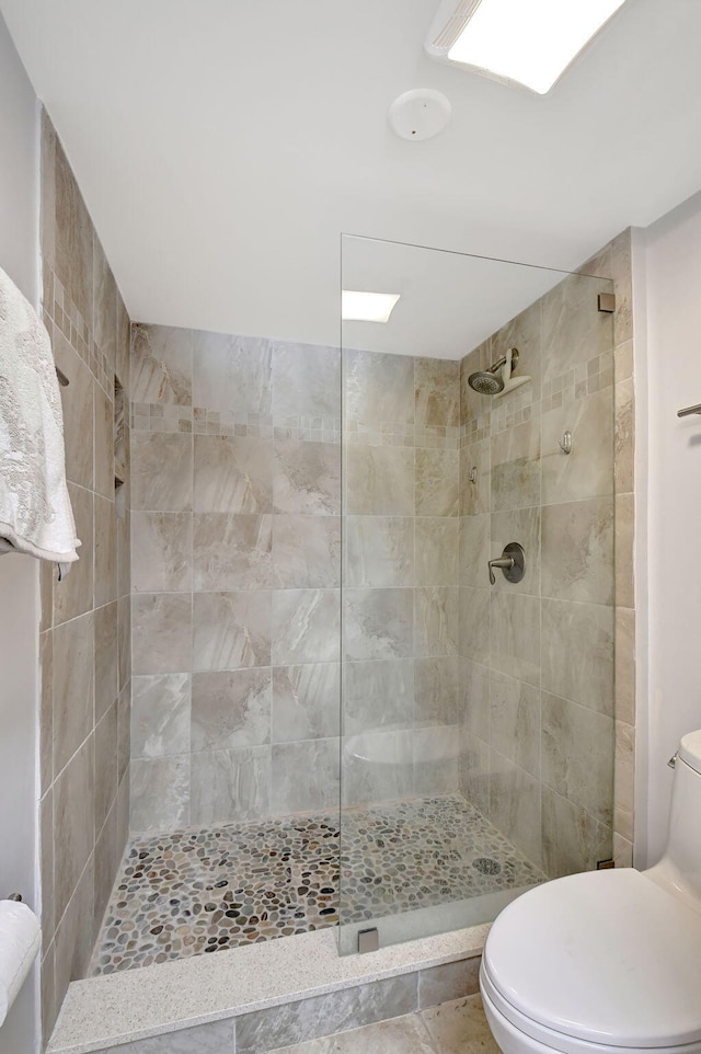 bathroom featuring tiled shower and toilet