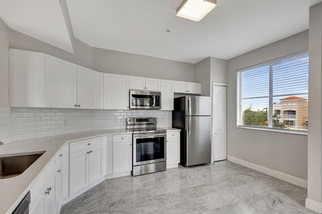 kitchen with white cabinets, decorative backsplash, stainless steel appliances, and sink