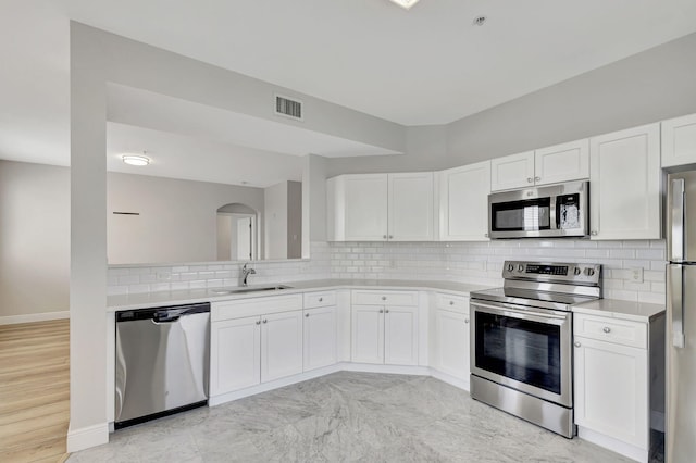 kitchen featuring backsplash, white cabinetry, sink, and appliances with stainless steel finishes