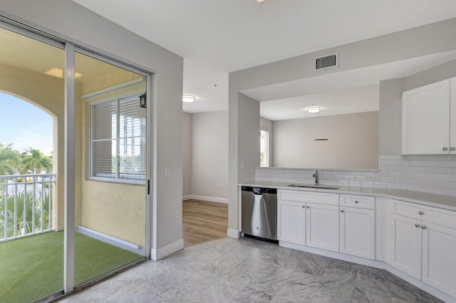 kitchen featuring white cabinets, tasteful backsplash, stainless steel dishwasher, and sink