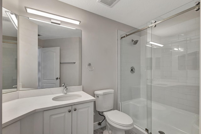 bathroom featuring vanity, a textured ceiling, toilet, and a shower with shower door