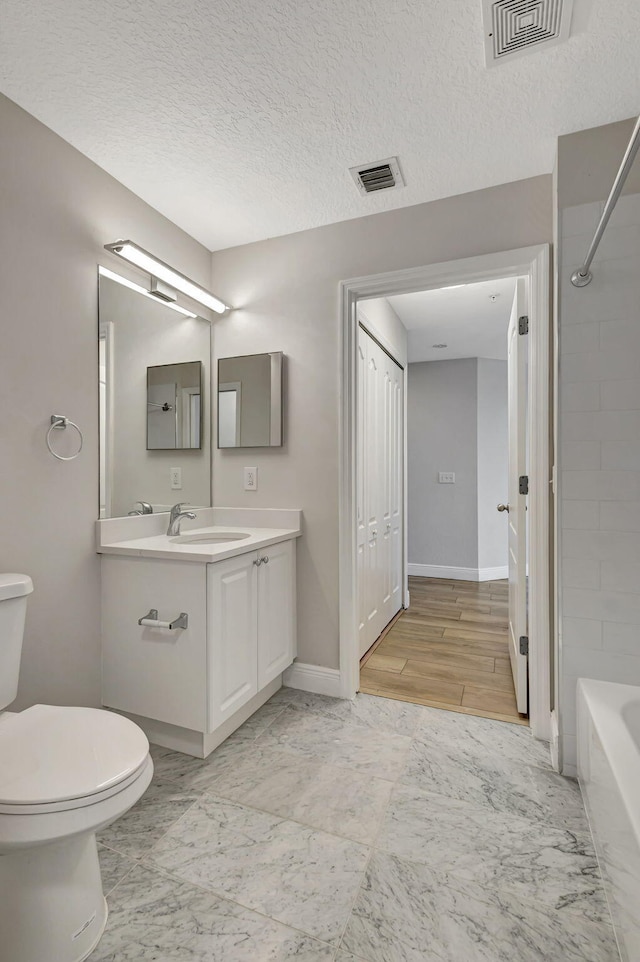 full bathroom featuring a textured ceiling, vanity, shower / bathtub combination, and toilet