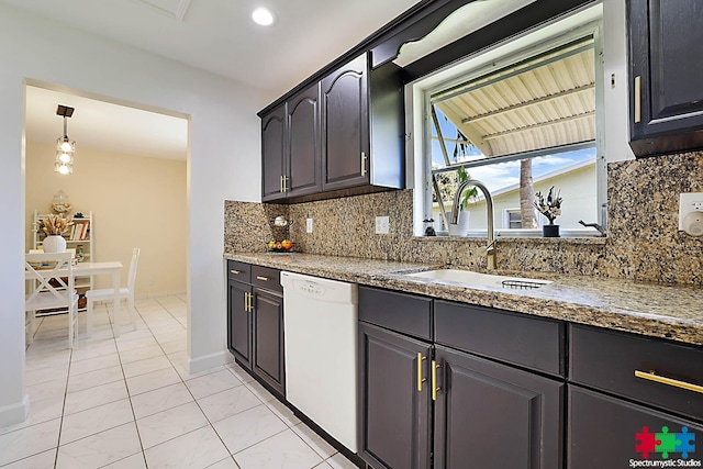 kitchen featuring tasteful backsplash, dark stone counters, white dishwasher, sink, and light tile patterned floors