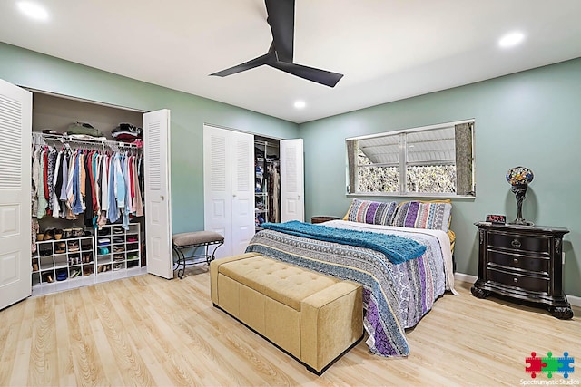 bedroom with hardwood / wood-style floors, ceiling fan, and multiple closets