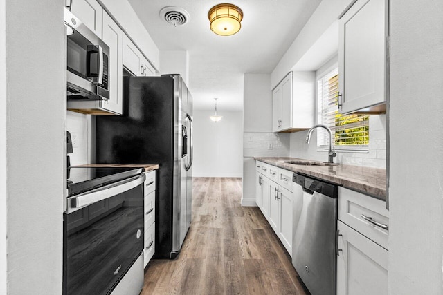 kitchen featuring sink, stainless steel appliances, dark hardwood / wood-style floors, stone countertops, and white cabinets