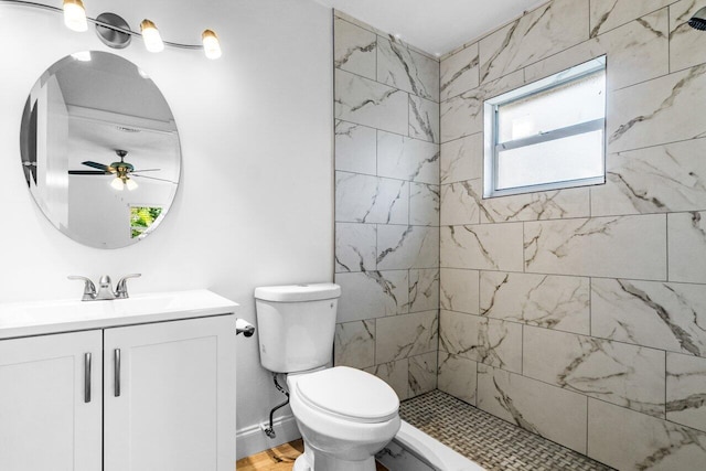 bathroom featuring a tile shower, ceiling fan, vanity, and toilet