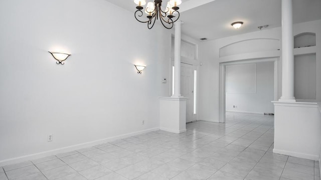 unfurnished room featuring decorative columns and a chandelier