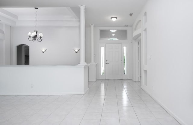 tiled entryway featuring decorative columns and a chandelier