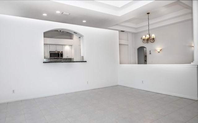 spare room featuring a tray ceiling and a notable chandelier