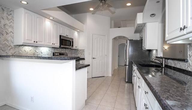 kitchen featuring dark stone countertops, sink, white cabinets, and light tile patterned flooring