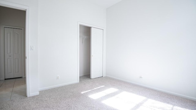 unfurnished bedroom featuring light colored carpet and a closet