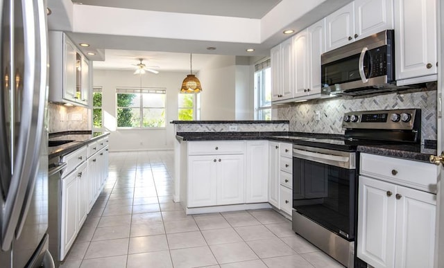 kitchen with kitchen peninsula, backsplash, stainless steel appliances, ceiling fan, and white cabinets